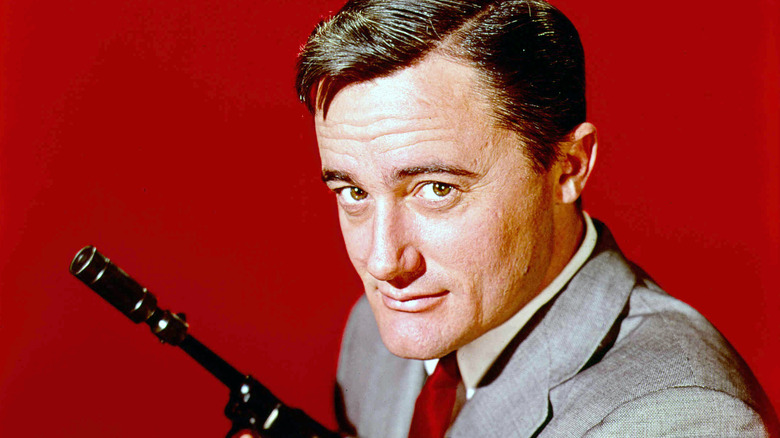 Napoleon Solo holds a gun and smirks