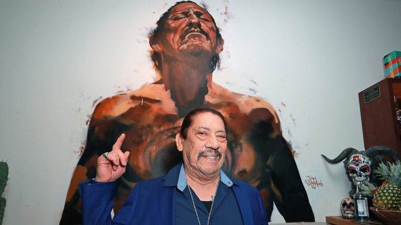 Danny Trejo points to a painting of himself in London in 2024