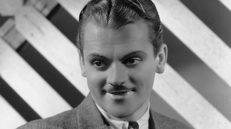 James Cagney in front of a white fence