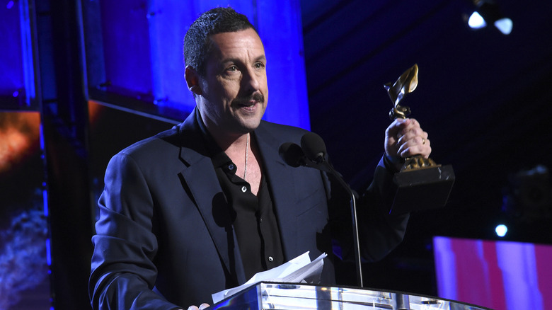 Adam Sandler holds an award