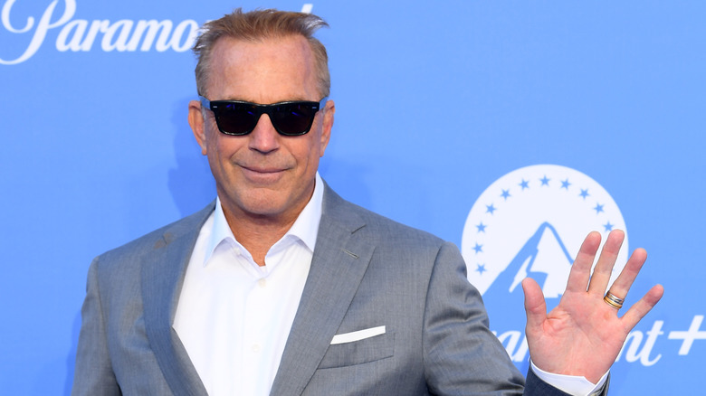 Kevin Costner smiles and waves