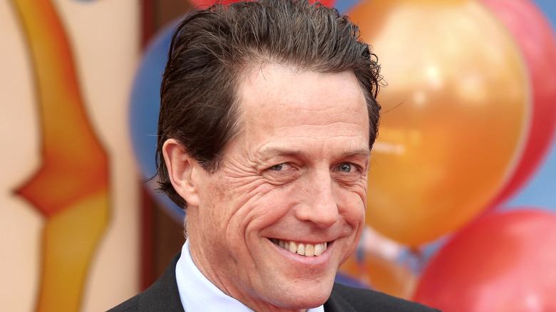 Hugh Grant smiles at a red carpet event