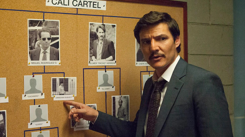 Javier Peña points at a board with suspects