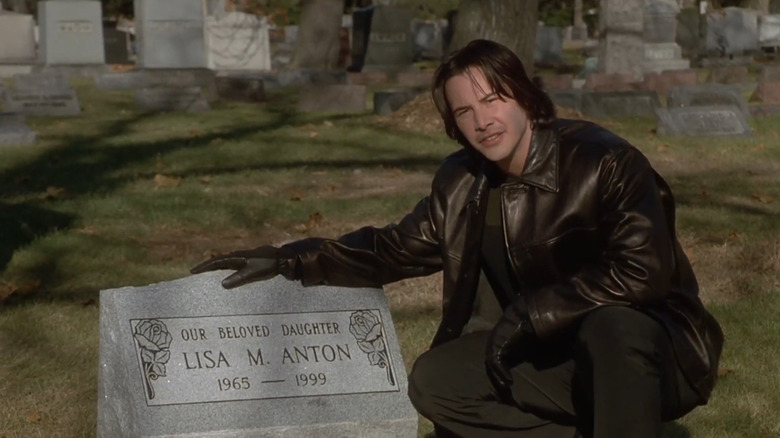 David crouching beside gravestone