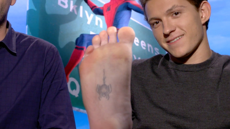 Tom Holland holding up foot
