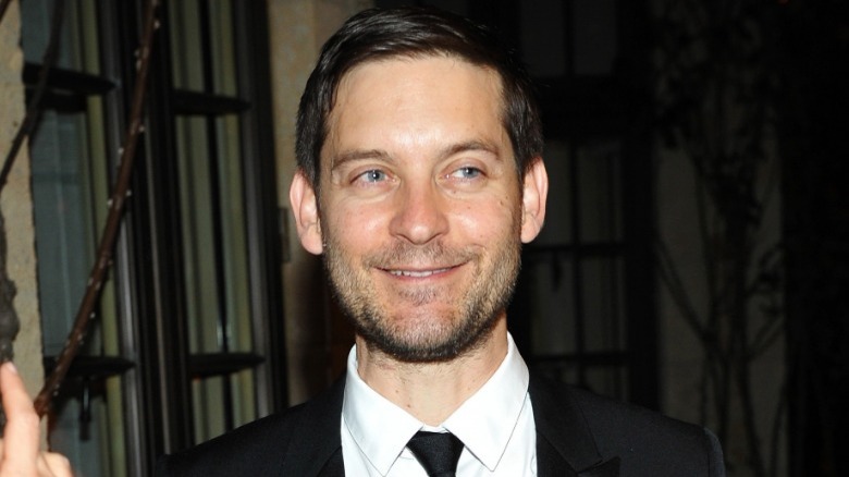 Tobey Maguire smiling in a suit