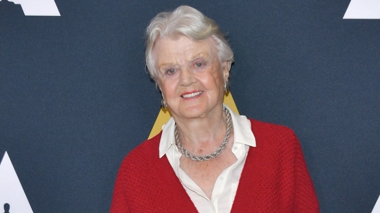 Angela Lansbury smiles in red sweater