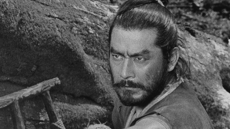 Mifune stands by a rockface