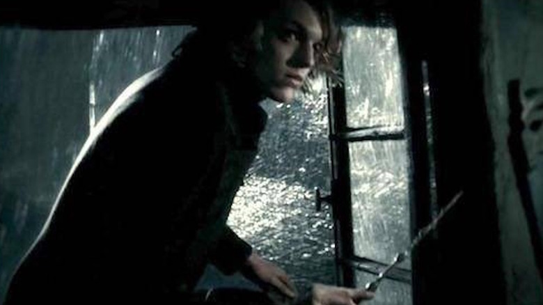 Jamie Campbell Bower holds a wand