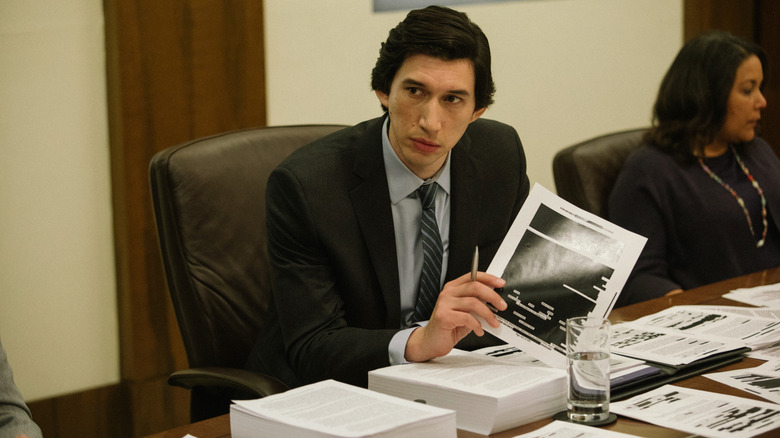 Adam Driver holding redacted paperwork