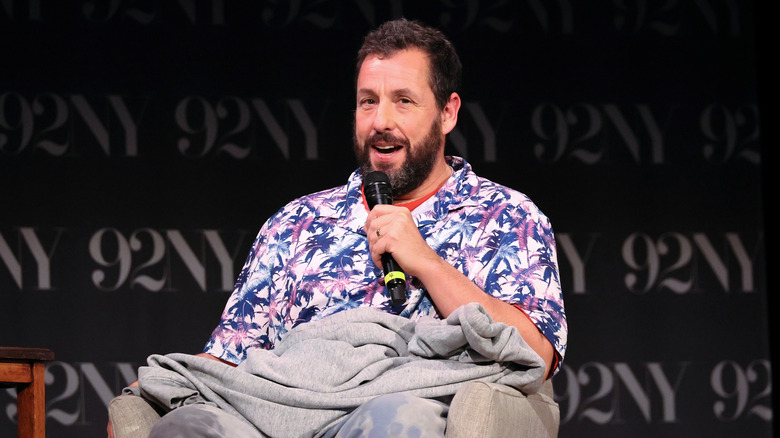 Adam Sandler talking into microphone