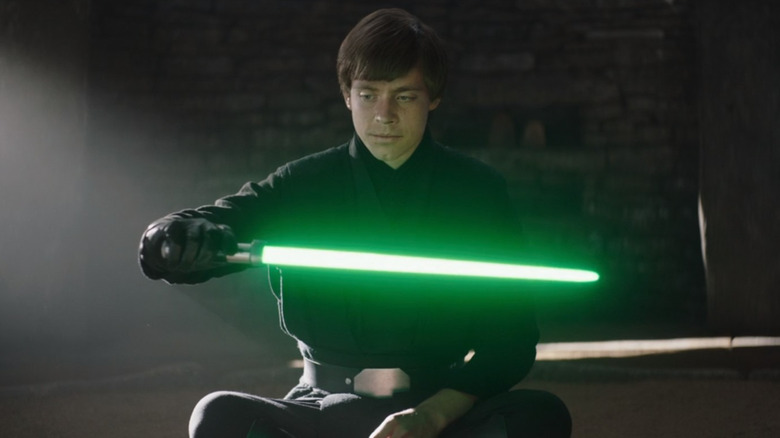 Luke Skywalker holds Yoda's lightsaber