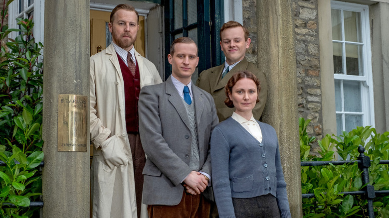 James Herriot, Siegfried, Mrs. Hall, and Tristan stand in front of door