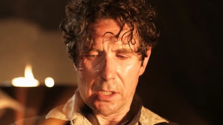 The Eighth Doctor locks frightened as he regenerates in a candle-lit room