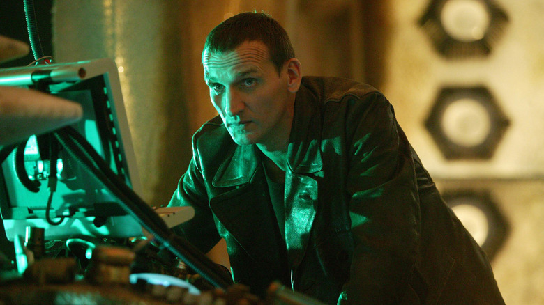 The Ninth Doctor leaning on the TARDIS looking concerned