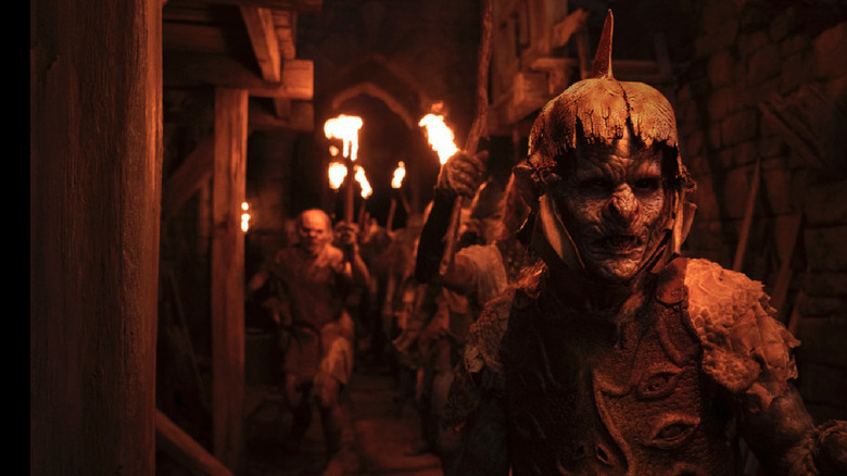 Orcs hold torches in tunnel