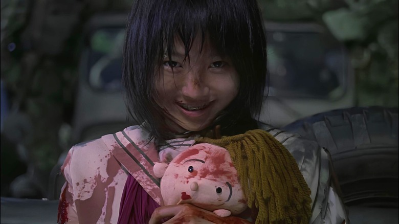 Mai clutches a blood-stained doll