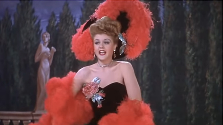 Angela Lansbury sings on stage with red feather hat