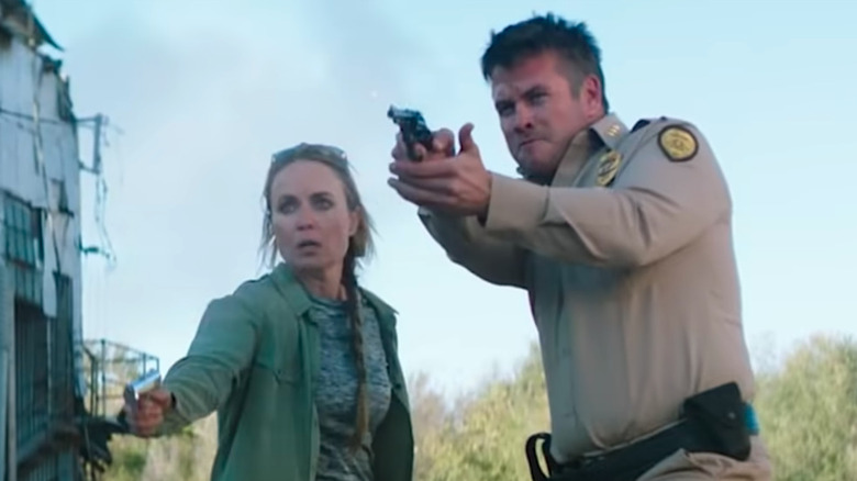 Radha Mitchell as Sal and Luke Hemsworth as Vernon firing guns in Asking For It