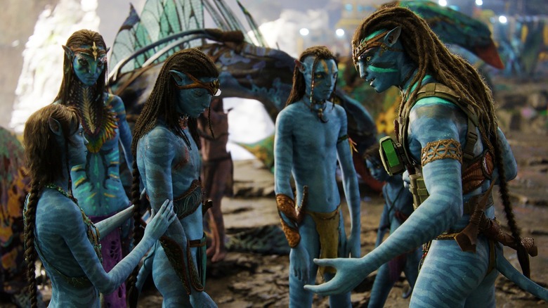 Zoe Saldana and Sam Worthington talking with other Na'vi in Avatar: The Way of Water