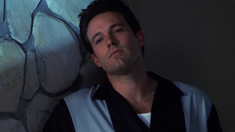 Ben Affleck leaning on wall staring