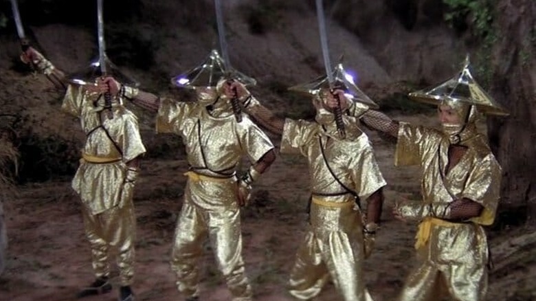 Four ninja hold up swords in golden outfits in Five Elements Ninjas (1982)