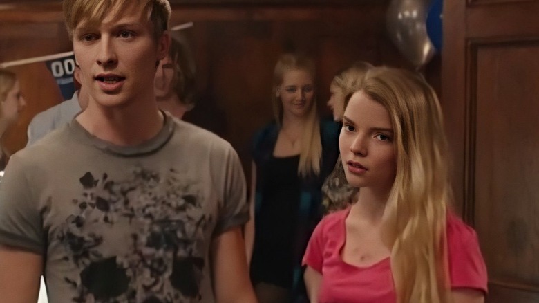 The Feeder Girl looks disinterested, standing beside a young man at a party