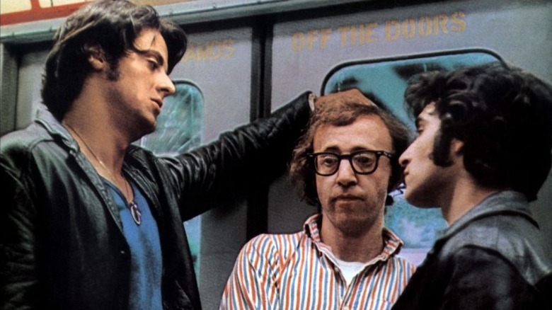 Fielding Mellish stares off-camera as two thugs in leather jackets tower over him on a subway train