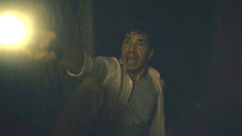 Justin Long scared holding a flashlight 