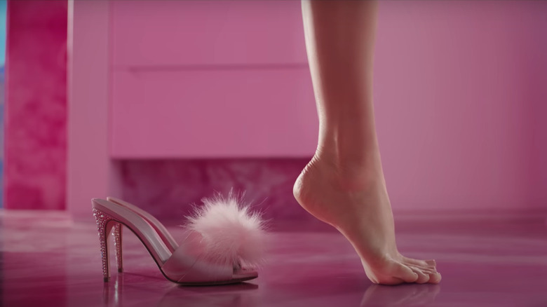 Barbie's arched foot next to pink high-heel shoe