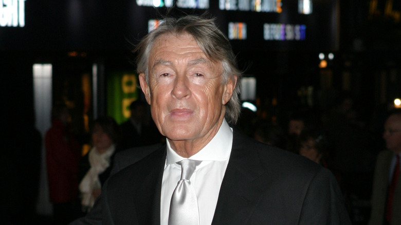 Joel Schumacher smiling wearing suit and tie