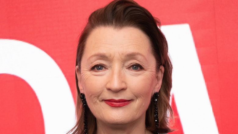 Leslie Manville smiling with red background