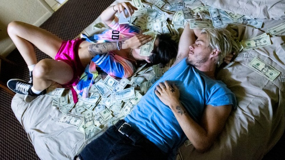 Arielle and Dean on a bed full of cash