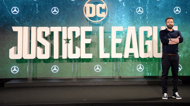 Ben Affleck standing in front of Justice League logo 