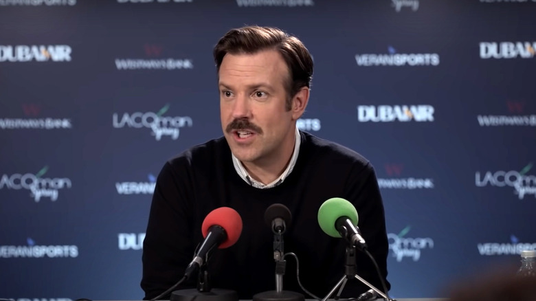 Ted Lasso speaking into microphones