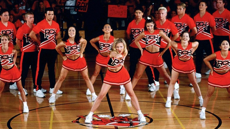 A high school cheerleading team performs on a gym floor