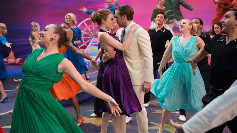 Several people dance on a brightly-colored recreation of the Hollywood Walk of Fame