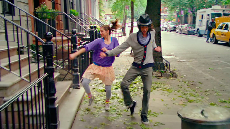 A young man and woman dance together on a sidewalk