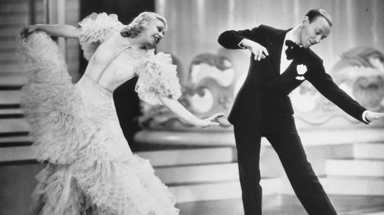 A dapper man and woman strike an elegant dance pose