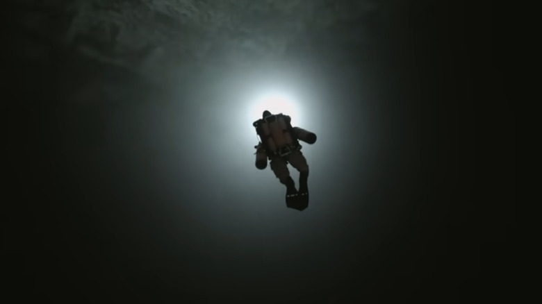 cave diver swims through darkness