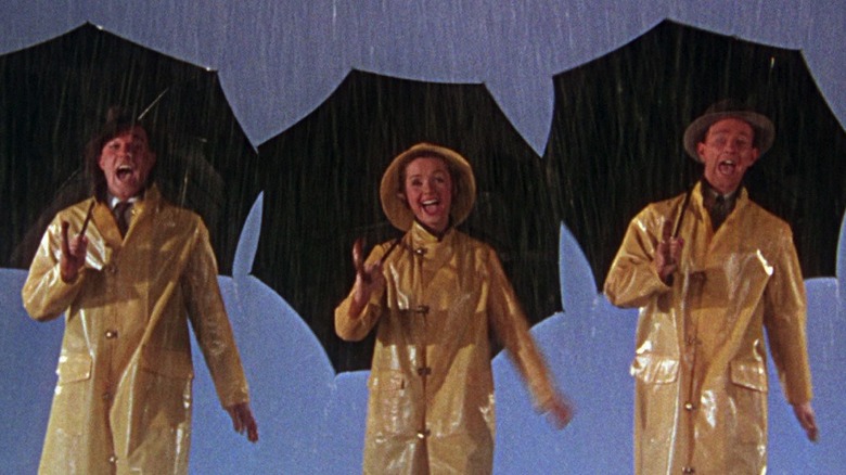 Three people singing with umbrellas