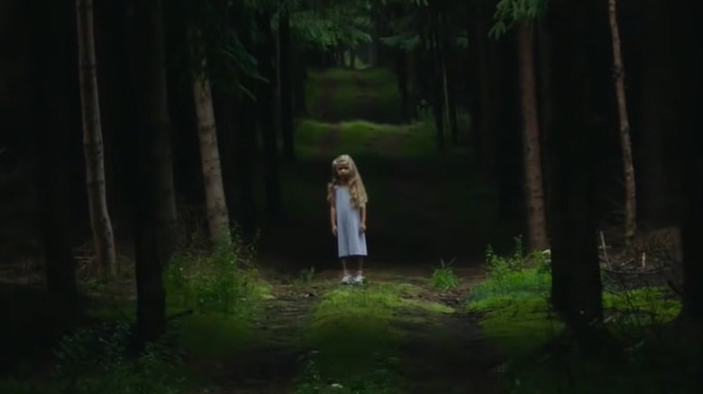 Little girl standing in woods