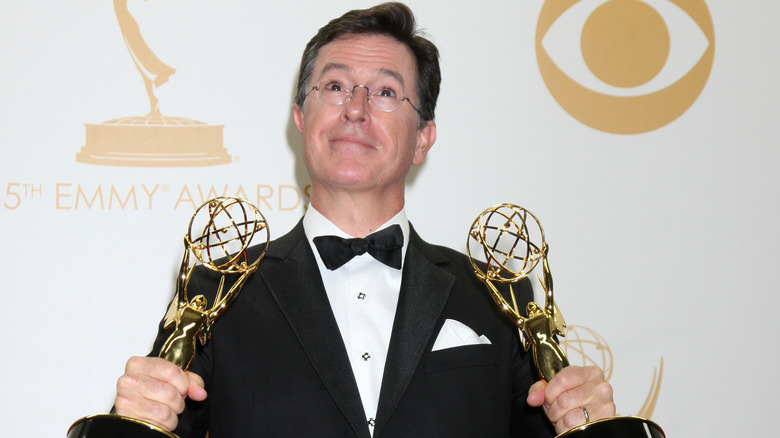 Stephen Colbert holding Emmy Awards