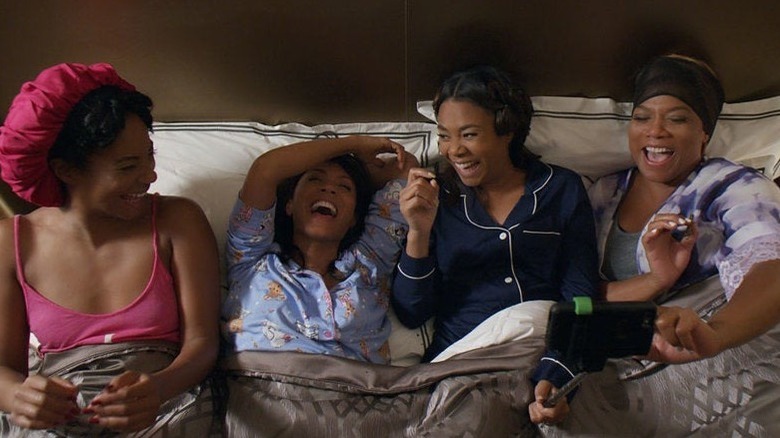 The cast of Girls Trip laughing in a bed