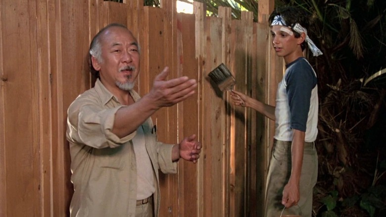 Mr. Miyagi has Daniel LaRusso paint fence