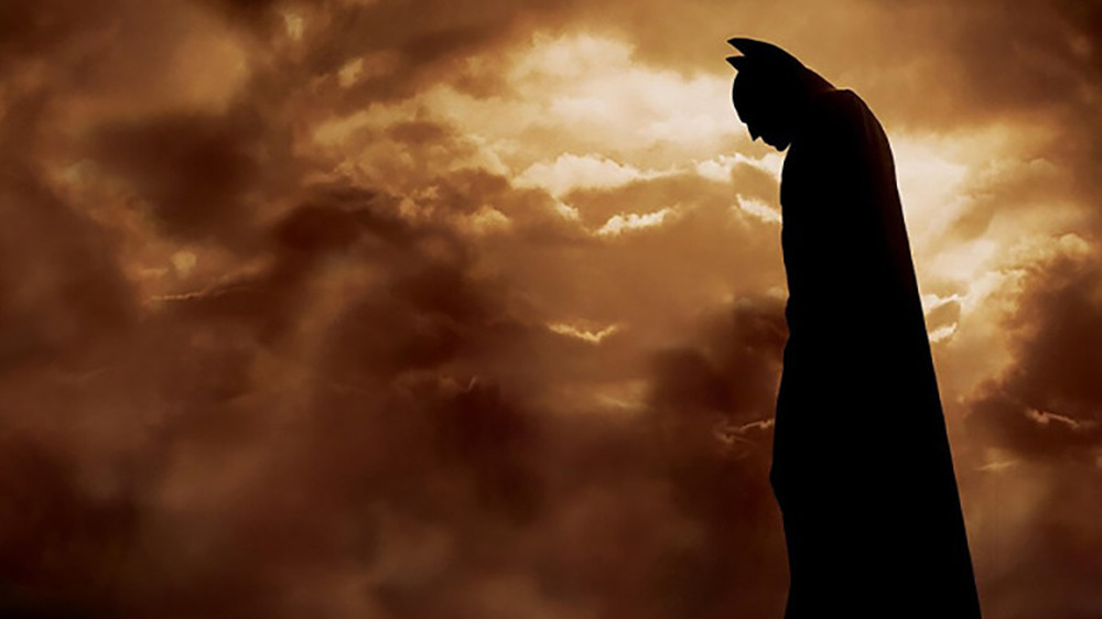 Batman looking down with a dusty sky behind him