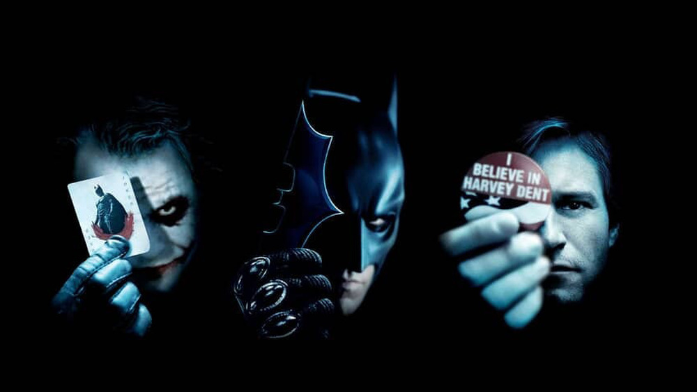 Main characters of Dark Knight holding up symbols