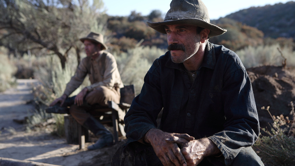 Daniel Plainview sitting focused outside