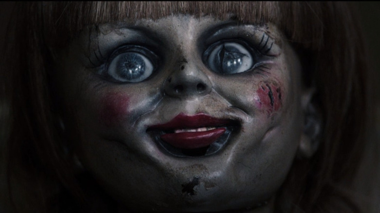 Close-up of Annabelle the doll, eyes wide open and grinning creepily