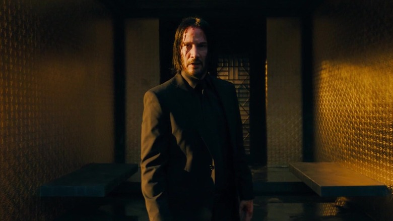 John Wick standing bloody in suit